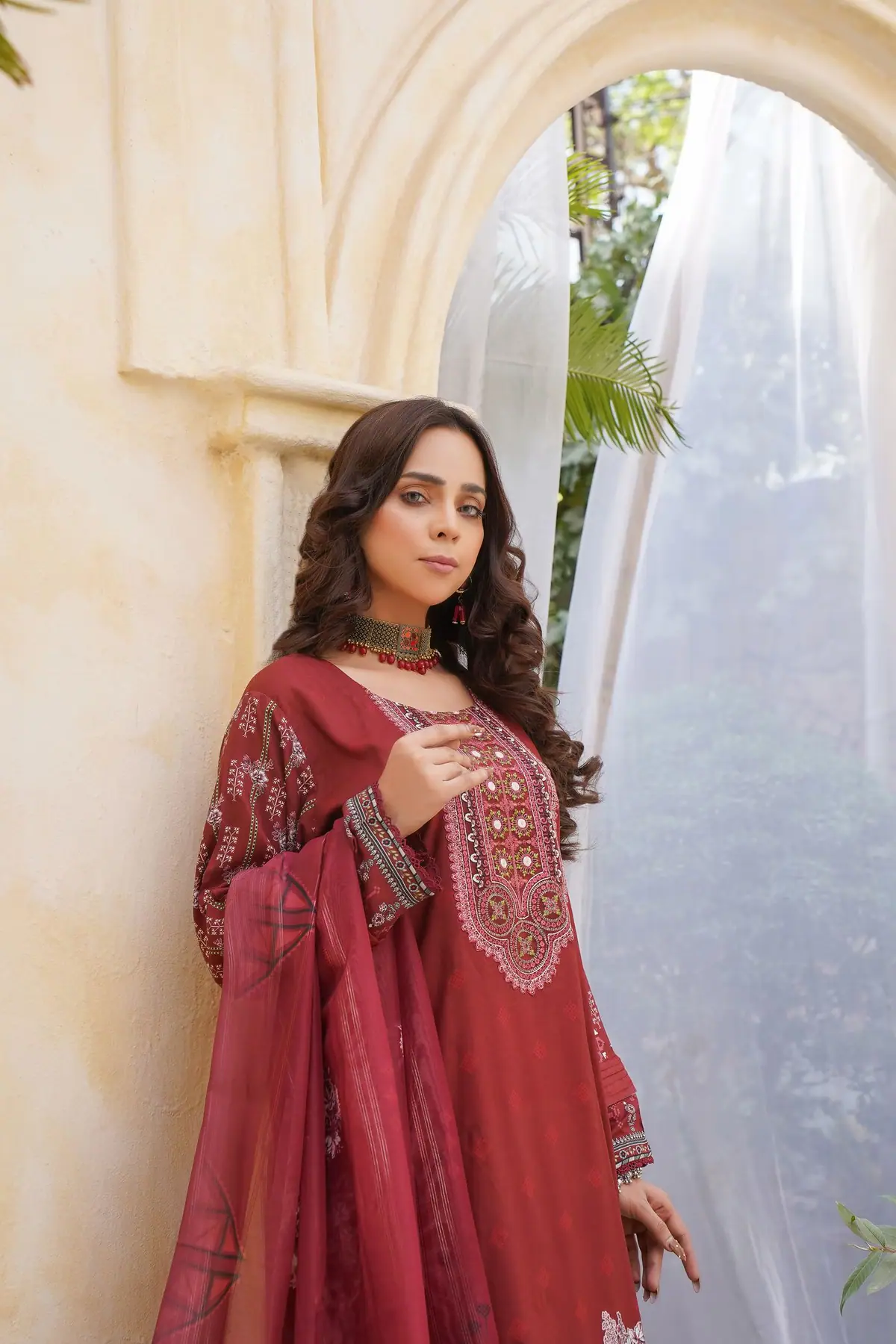 Model wearing a red traditional Pakistani ensemble